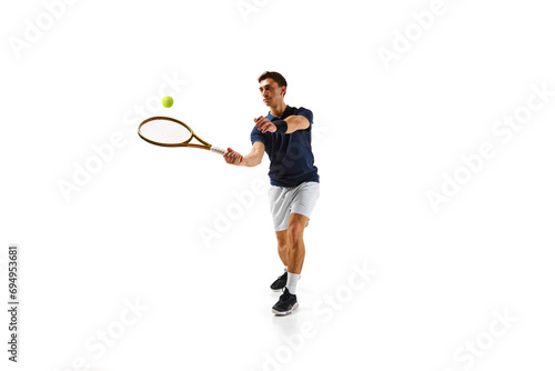 Competitive man in his 30s, tennis player in motion, hitting ball with racket, practicing isolated over white background. Concept of professional sport, competition, game, math, hobby, action © master1305