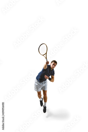 Full-length top view image of man, tennis player during game, in motion, hitting ball with racket isolated over white background. Concept of professional sport, competition, game, math, hobby, action