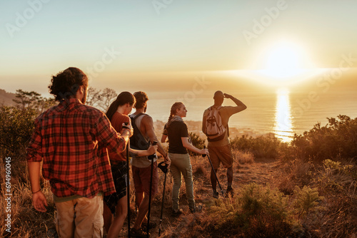 Young hikers standing on mountain top watching sunset photo