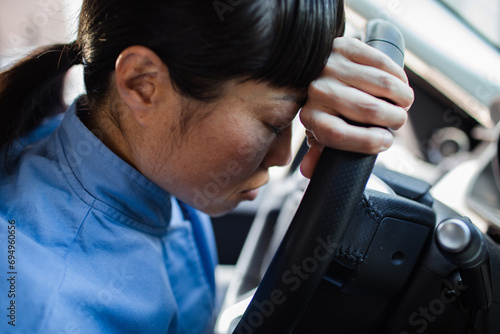 Asian woman resting head on steering wheel photo