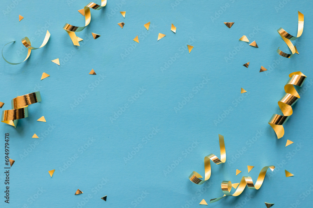Samolepka close up on group of gold color of rolling ribbon and confetti on teal backgroun