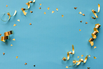 close up on group of gold color of rolling ribbon and confetti on teal background with copy space for christmas festival happy new year ,carnival , birthday and anniversary, concept design