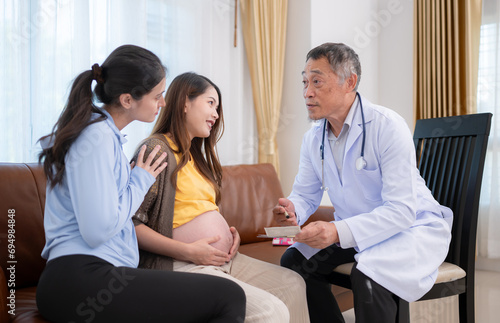 Asian pregnant woman and her friend visit gynecologist doctor at medical clinic for pregnancy consultant. The doctor explains the results of the health examination of the baby and mother.