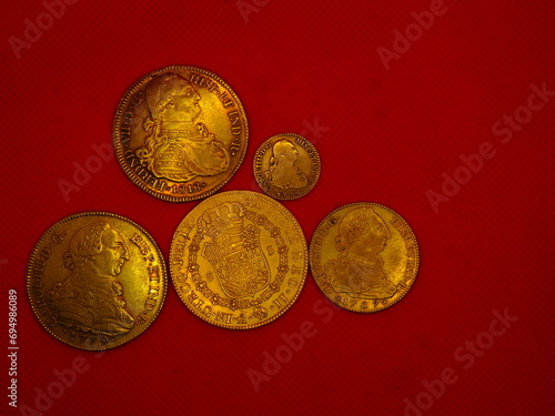 Spanish gold and silver coins, Shields and Reales, on a red background photo