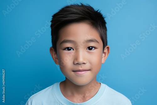Asian Boy with a Soft Smile on Blue Background