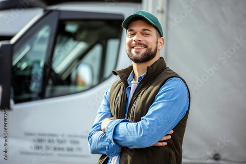 Happy confident male driver standing in front on his truck photo