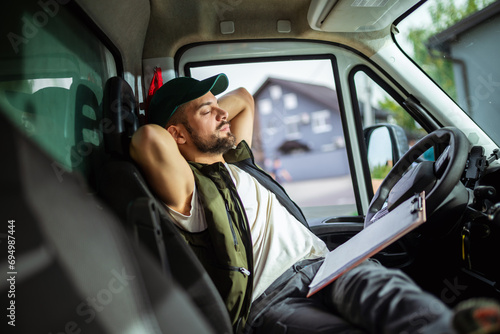 A tired truck driver takes a break from driving and rests in his truck