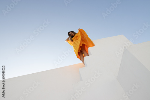 Girl in orange dress on white background with blue sky