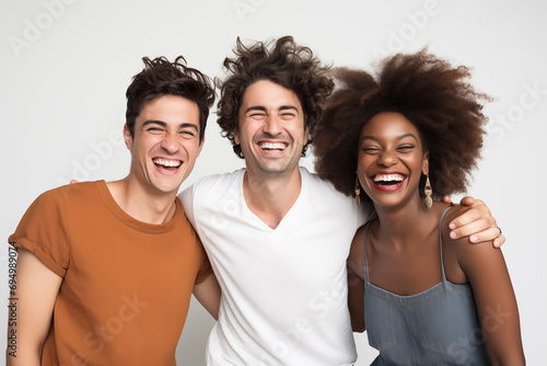 Photograph of three friends posing together in a medium shot, smiling, and looking at the camera against a white background