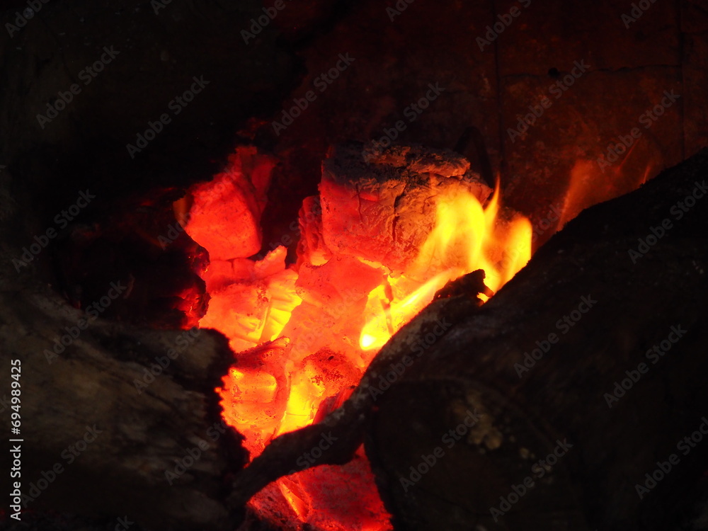 Yellow and orange flames over the embers of a winter bonfire