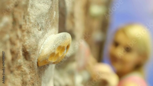 Girl clings to extending stone on climbing wall. Focus on stone photo