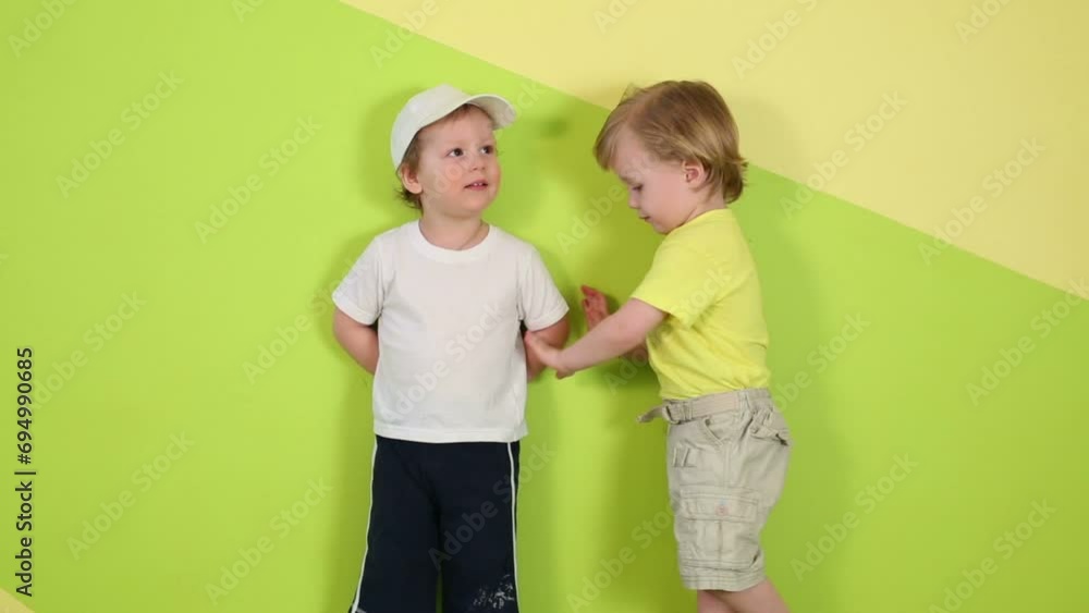Little cute boy dance and other boy stands near green wall Little cute boy dance and other boy stands near green wall