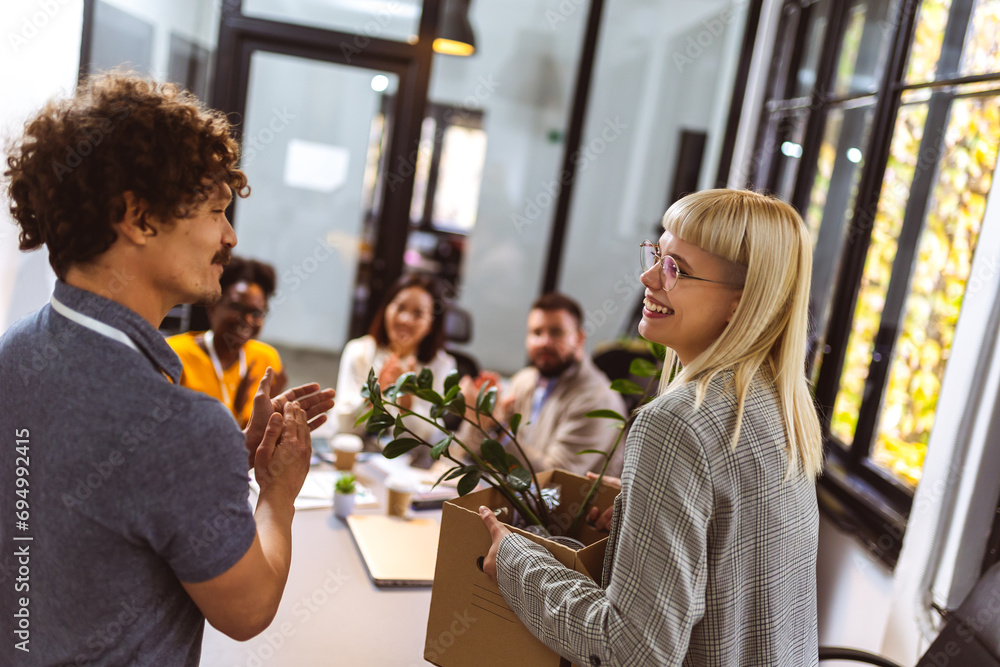 Business team meets a new employee. New coworker holding a box standing in the modern office with other colleagues Business team meets a new employee. New coworker holding a box standing in the modern office with other colleagues