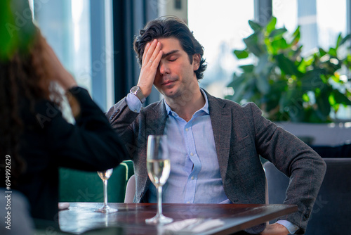 portrait of an upset nervous man sitting in a restaurant with a girl who is quarreling on a date conflict photo
