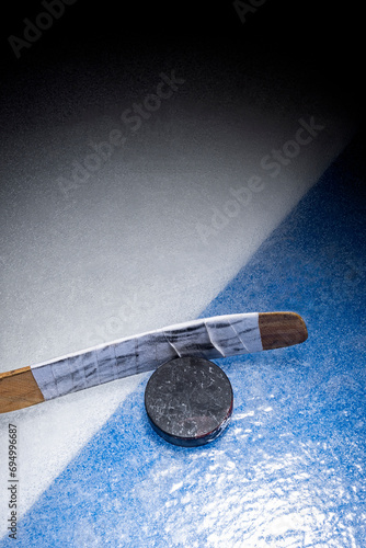 Photography Looking down on an ice hockey puck and stick at the blue line
