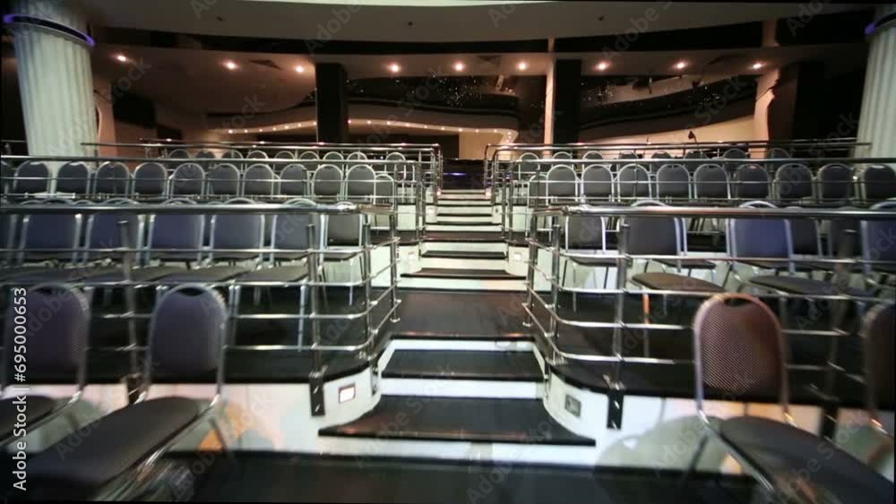 Stairs among rows of seats in empty illuminated auditorium Stairs among rows of seats in empty illuminated auditorium