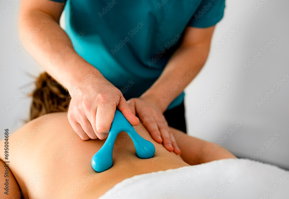 Fototapeta premium masseur doing back massage with special massage accessories