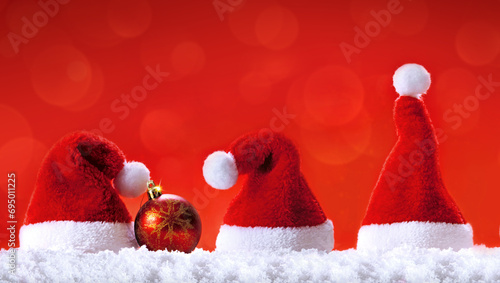 Christmas bauble and red Santa hats on white snow.