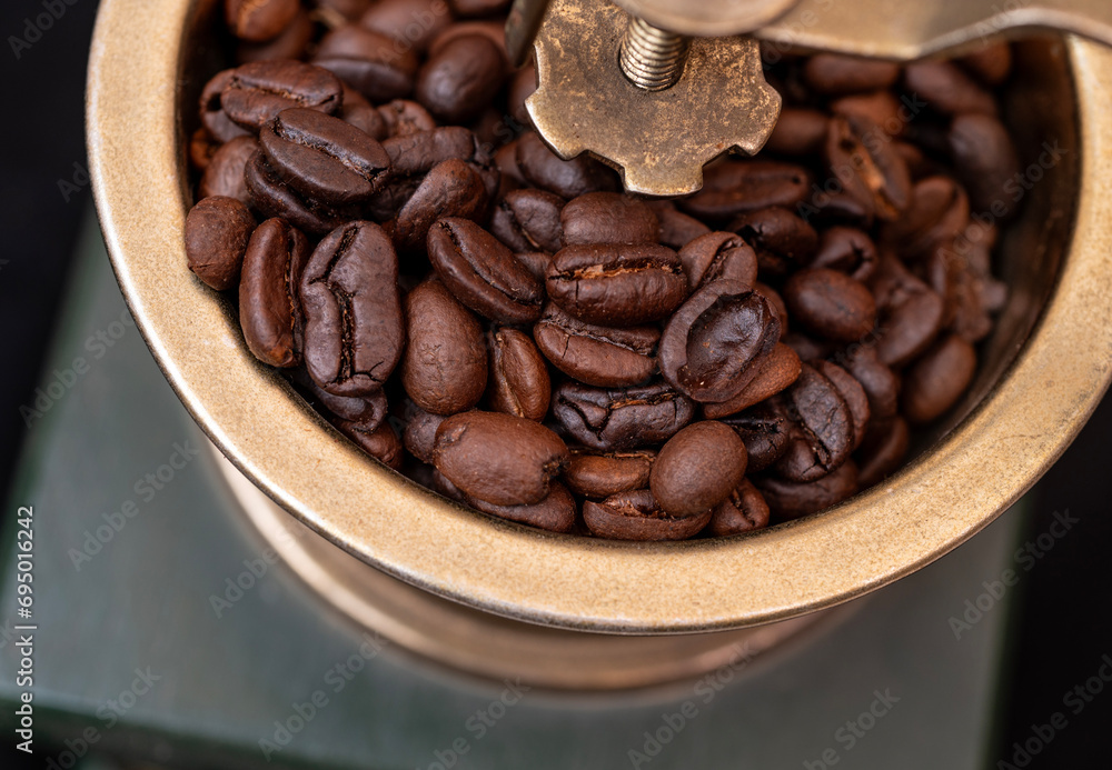 Fototapeta premium Closeup view of golden coffee grinder with roasted beans