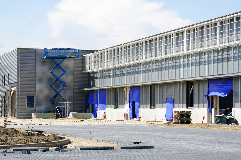 Unfinished modern commercial building facade fragment, self propelled scissor lift Unfinished modern commercial building facade fragment, self propelled scissor lift