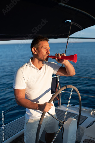 Man in a white tshirt on a yacht with a megaphone in hand