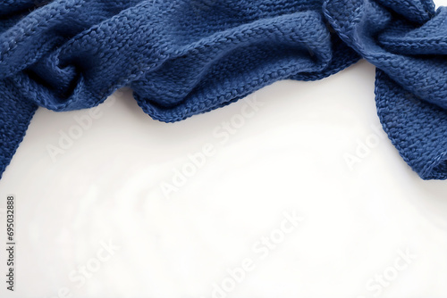 Homemade blue knitted woolen scarf on white background