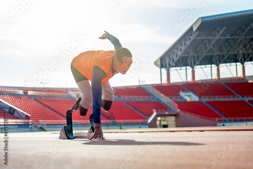 Sport man athlete prosthesis legs stay in the position of start running and look forward at the stadium with soft light of evening.