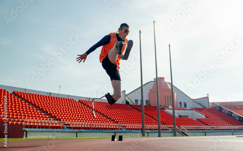 Sport man athlete prosthesis legs jump up in front of sun light in the afternoon of the stadium.