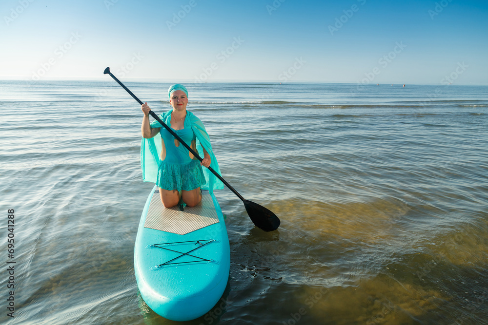 A Jewish woman in a turquoise bathing suit with a skirt and a headscarf
