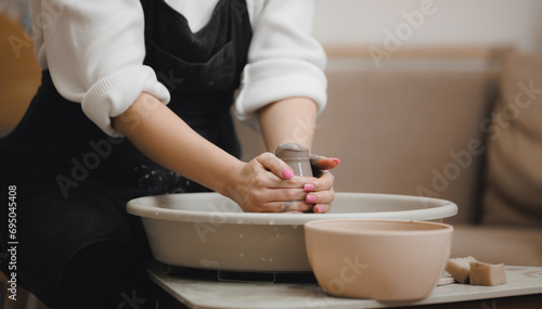 Hands of young girl with manicure master on potter wheel makes clay dishes. Art workshop place for relax business