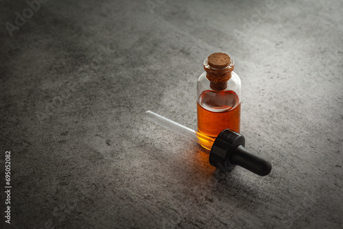 A round glass bottle containing dark orange color essential oil for cosmetics and natural medicine with dropper. photo