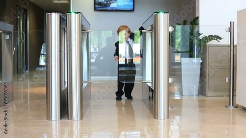 Little boy in suit goes glass turnstile in business center photo