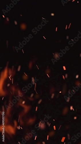 ultra slow motion high speed shot of fire flames and glowing ash particles on black background - vertical video for reel and story photo