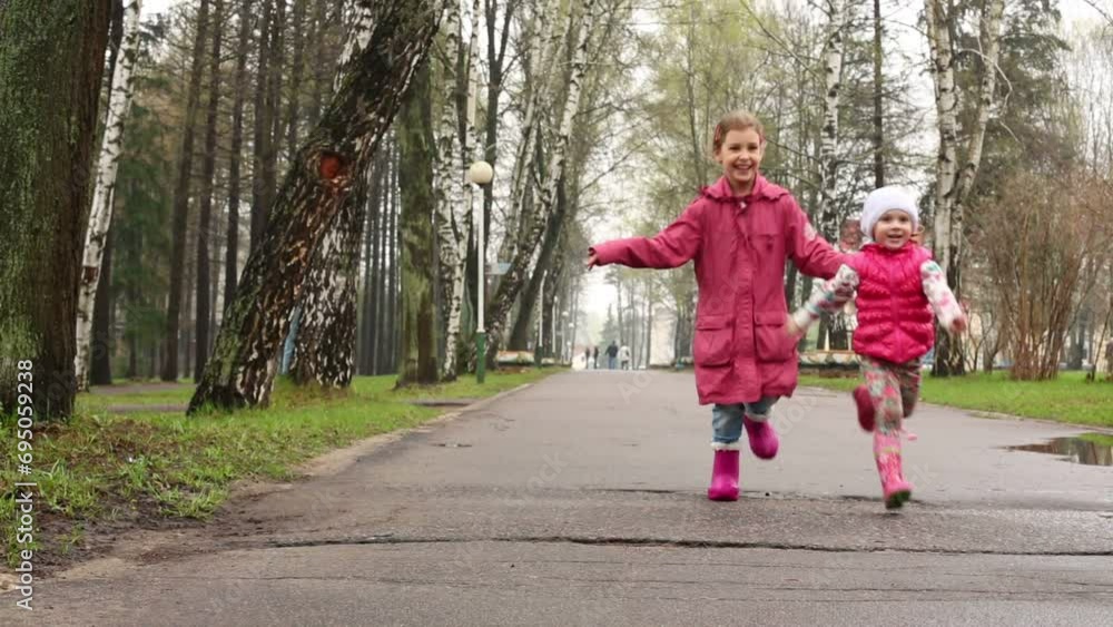 Two happy little girls run on alley with wet asphalt Two happy little girls run on alley with wet asphalt