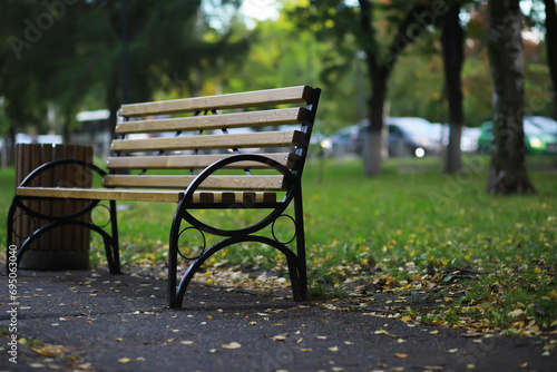 Autumnal park with bench. Falling leaves. Focus on bench