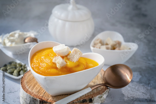 Pureed pumpkin soup with sesame seeds and pumpkin seeds in a heart-shaped plate. All-season vegan diet soup