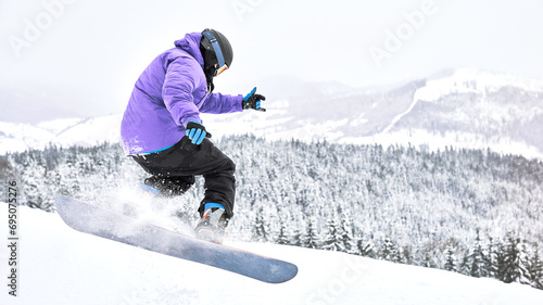 Shot of the freeride snowboarder that is making some trick while riding down from the hill. Extreme winter sport