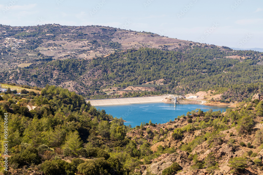Hilly landscape with a water reservoir. Blue mountain water in the reservoir