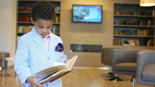 Cute mulatto boy in jacket holds book in hand and reads photo