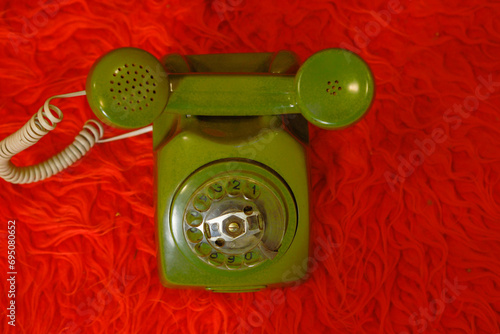 Old green telephone on a red background with an upside down receiver