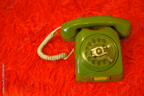 Old green telephone on a red background
