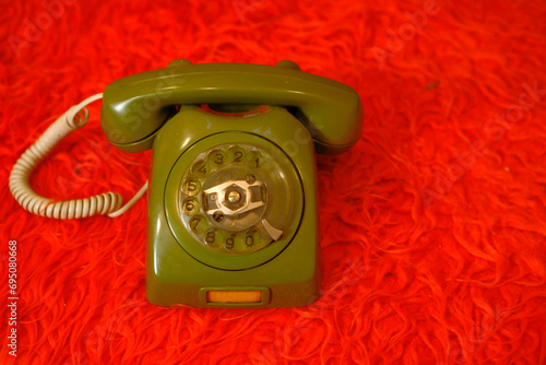 Old green telephone on a red background