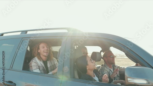 Cheerful multinational friends singing and riding in car in summertime