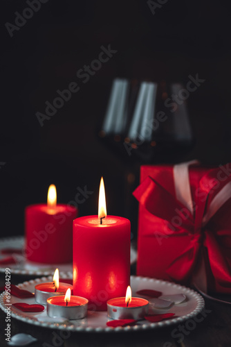 Saint Valentine's Day celebration. Red burning candles, hearts, gift box, postcard on dark wooden background. Happy holiday . Table decor for festive dinner, romantic atmosphere. Copy space for text photo