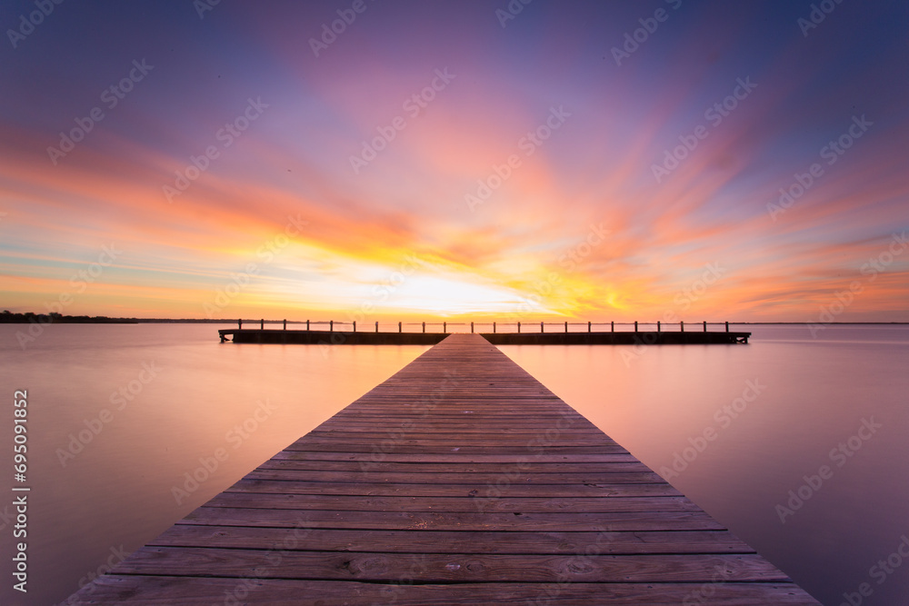 Sunset sunrise with a colorful sky over a wooden boardwalk at the beach.  Colorful nature background that encourages hope, happiness, positivity, and optimism.