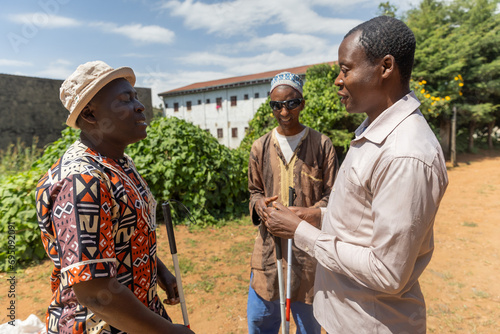 Three blind men on a beautiful sunny day chatting while standing outside in the yard