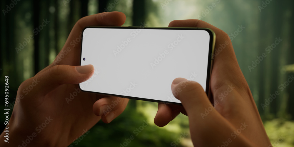 CU Man using his phone outdoors in the forest during hiking or camping trip CU Man using his phone outdoors in the forest during hiking or camping trip