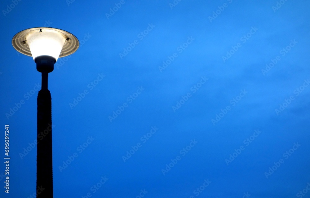 Old streetlight on blue sky with delicate clouds at sunset Old streetlight on blue sky with delicate clouds at sunset