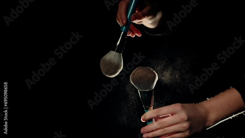 Girl shakes off face powder from the brush. Closeup of makeup brushes. Slowmotion, footage 4k.  photo