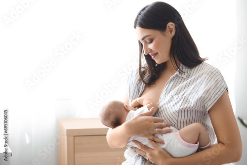Young woman breastfeeding her baby at home photo